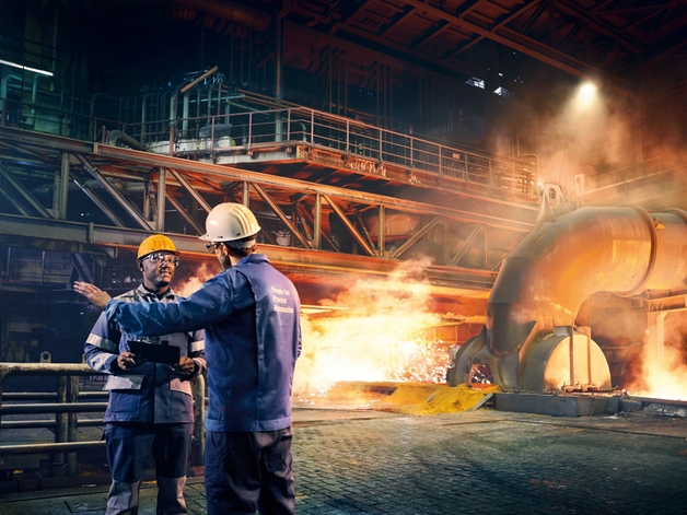Два инженера обсуждают на металлургическом заводе.